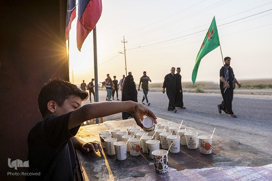 A boy offers drinks to pilgrims attending Arbaeen walk in September 2022.